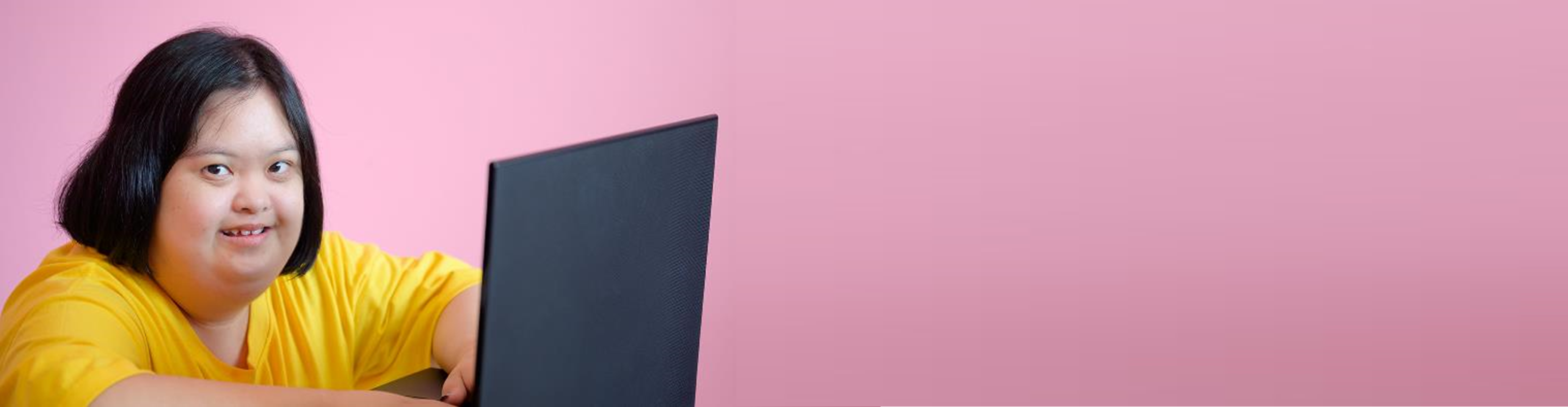 A woman wearing a yellow top is working on a laptop.