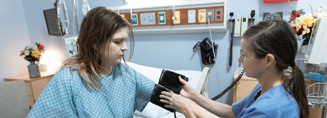 A young woman in a hospital is having her blood pressure measured