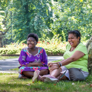 2 women sitting on the grass in a park on a sunny day