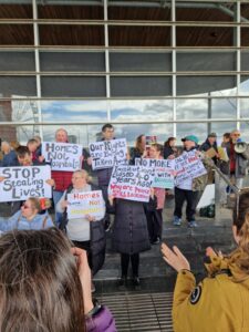 Group of people outside the Senedd all holding protest placards