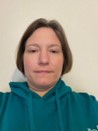 Lynne has short dark hair and is wearing a green hoodie.