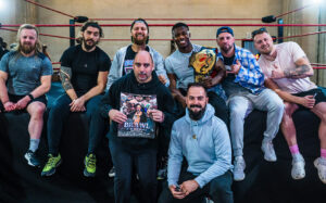 gig buddy friends sitting in front of a wrestling ring with a group of wrestlers
