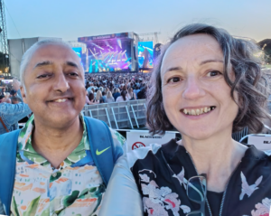 gig buddies at a large outdoor concert with the crowd and stage in the distance behind them