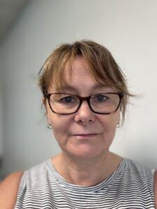 Julie has brunette hair in a bob and is wearing glasses