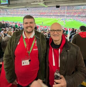 2 friends wearing Welsh rugby shirts watching rugby at Principality Stadium