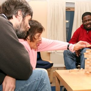 Three people in supported living playing a game of Jenga