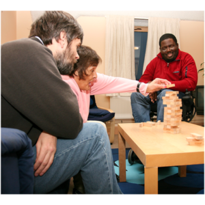 People sitting around a coffee table playing Jenga