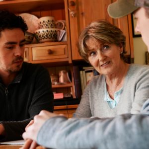 3 people sitting round kitchen table talking