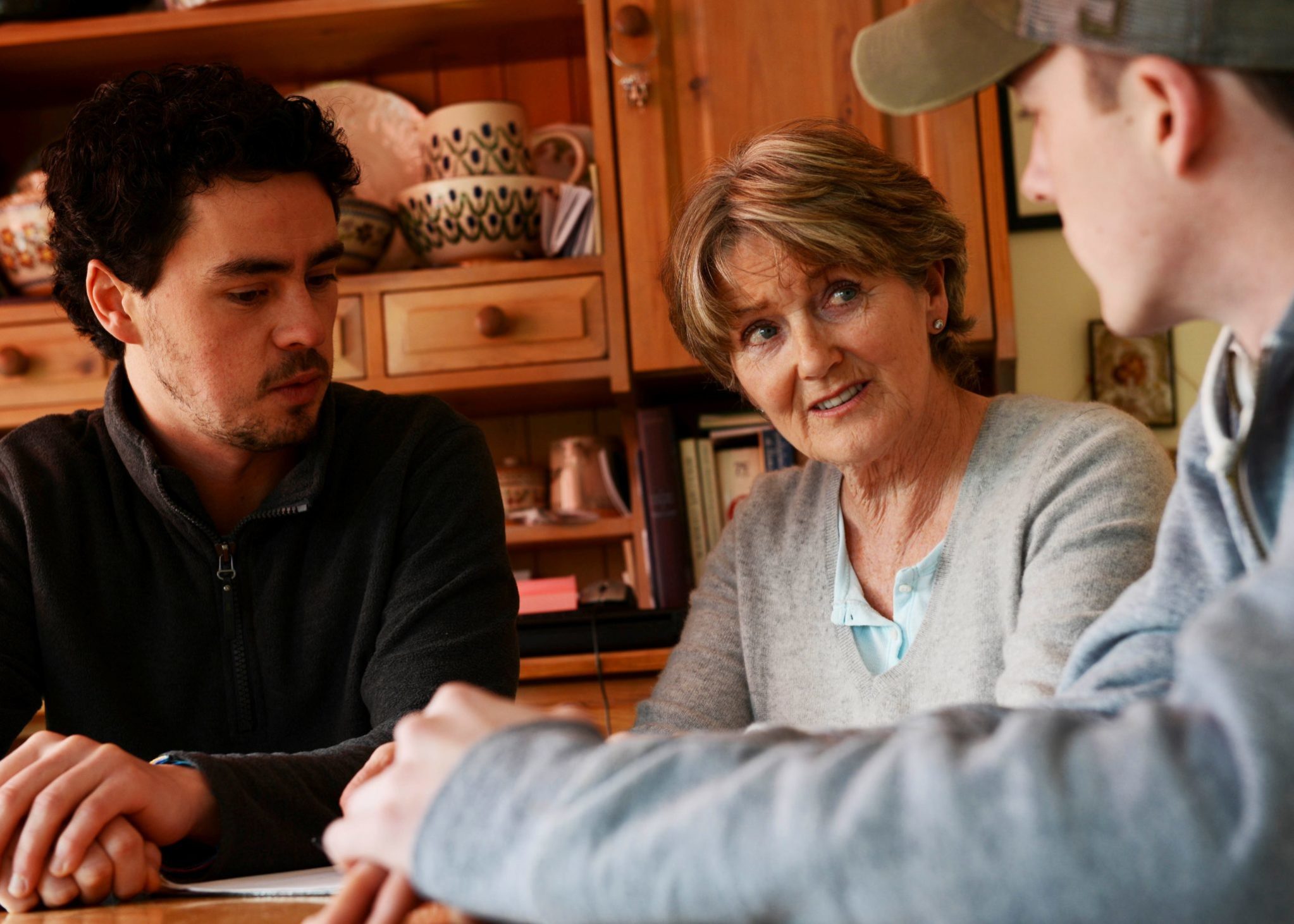 3 people sitting round kitchen table talking