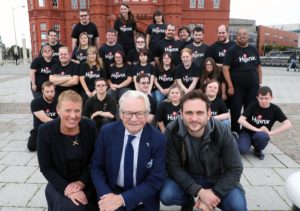 A group of actors from Hijinx Theatre and Lord Dafydd-Elis-Thomas in front of Cardiff's Pierhead Building