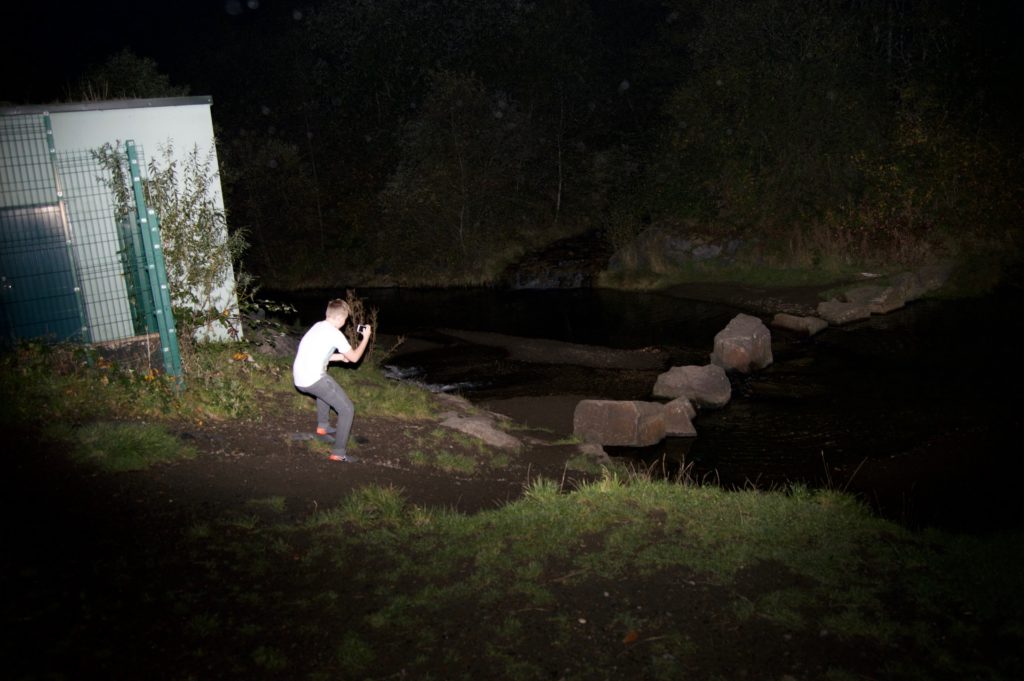 Picture of a young man taking a picture at night.