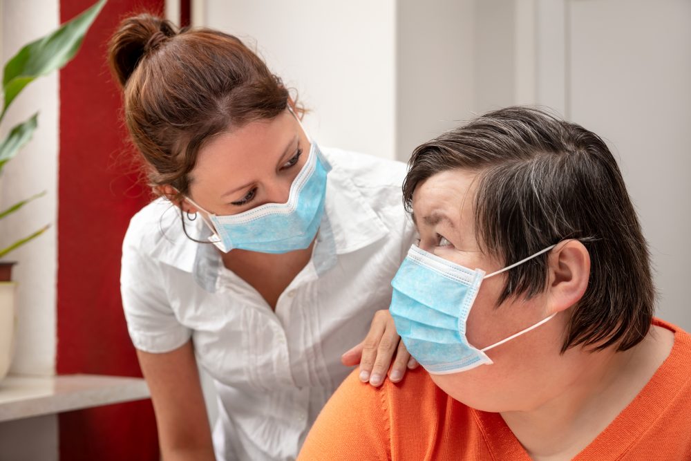 Woman with a learning disability wearing a mask talking to a support worker