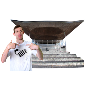 Young man standing in front of the Senedd building with his thumbs up