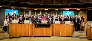 A large group of young people standing together in the Senedd chamber 