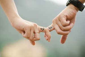 Close up of 2 people's hands, their fingers are intertwined 