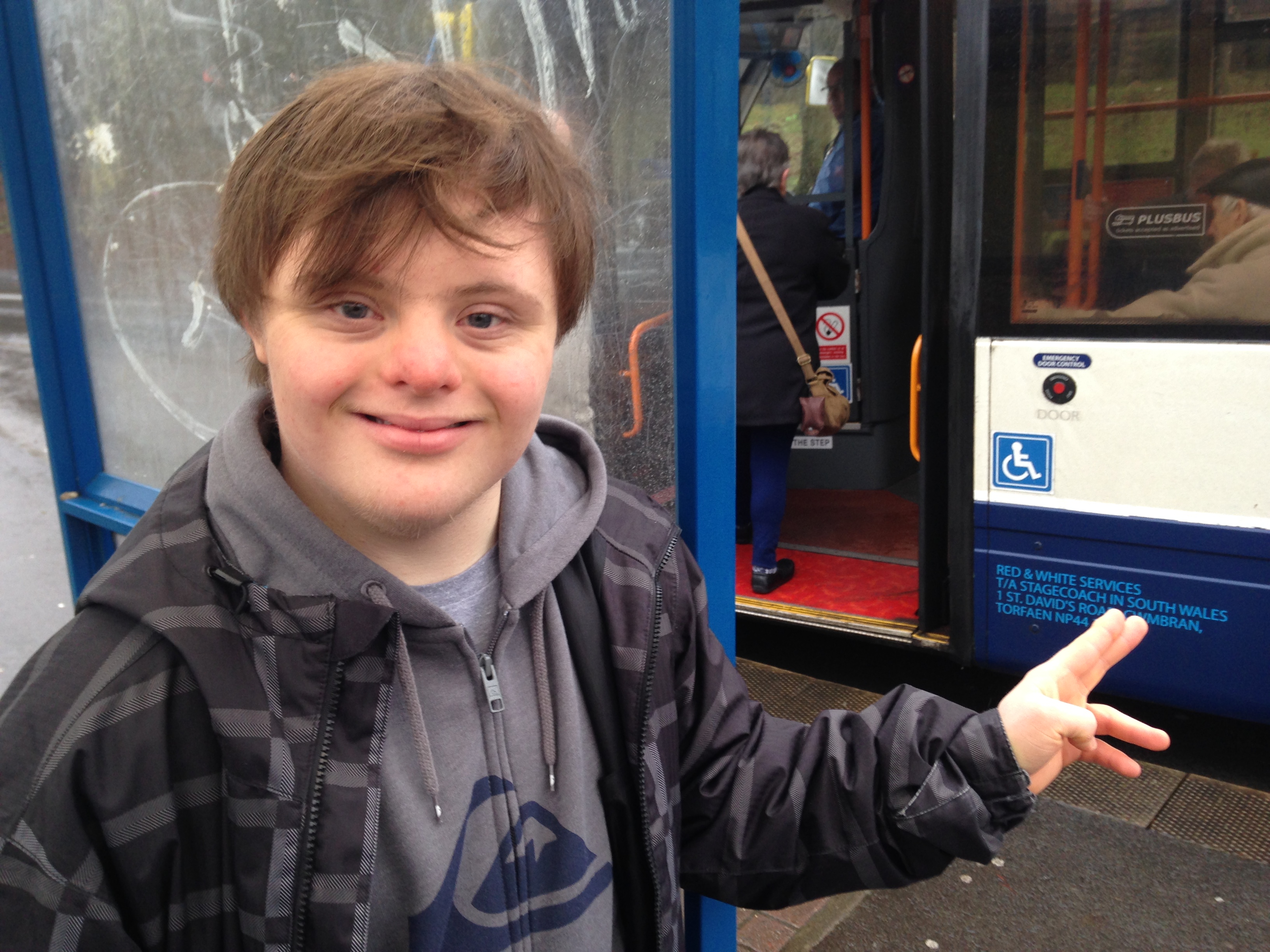 A young man standing next to a bus